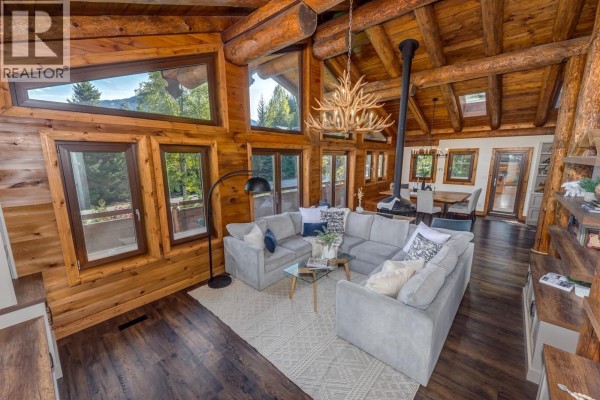 Living room with a large sectional sofa, fireplace, and mountain view through large windows. - 6403 St Andrew's Way, Whistler