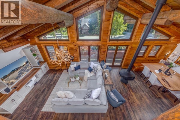 Open-concept living and dining area with a large sectional, dining table, and extensive wood detailing. - 6403 St Andrew's Way, Whistler
