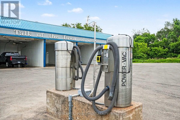 Two stainless steel vacuums with hoses are parked in front of car wash bays. - 641 Nelson Street, Pembroke