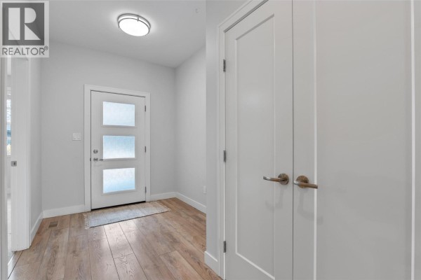 Interior entryway with light grey walls, white doors, and a frosted glass front door. - 641 Shuswap Road E Unit# 228, Kamloops