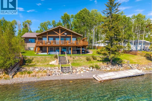 Drone view of a house with a brown roof and a covered carport by a lake. - 6410 Fox Crescent, Green Lake