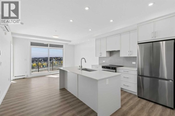 Open concept kitchen with white cabinets, island, and stainless steel appliances. - 6411, 1802 Mahogany Boulevard Se, Calgary