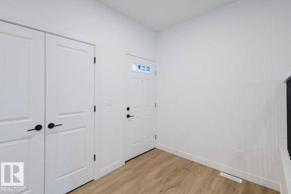 Open foyer with staircase, black railings, and access to living areas - 6411 27 Av Sw, Edmonton