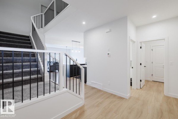 Staircase leading to upper floor with carpeted steps and view of living room - 6411 27 Av Sw, Edmonton