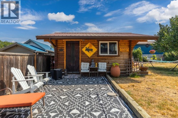 View of the backyard cabin with a roll-up glass door and a hammock set up nearby. - 6415 Glendora Way, Lavington