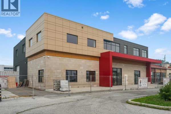 Side view of the commercial building, showing its modern facade and surrounding paved area. - 6415 Tecumseh Road East, Windsor