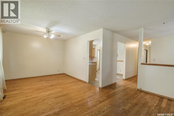 Interior view showing living room and hallway access to kitchen with hardwood floors and neutral walls. - 6418 7th Avenue N, Regina