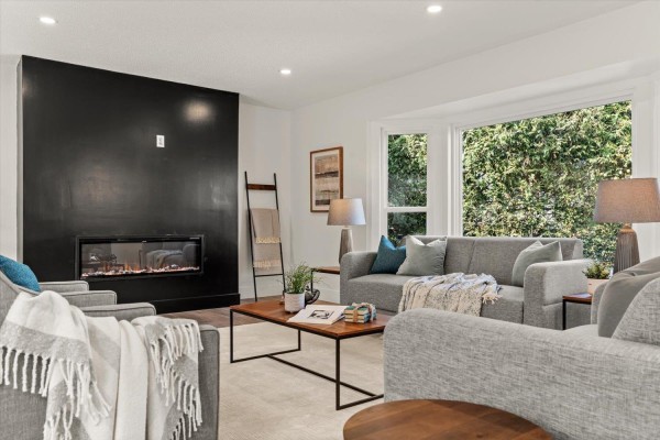 Interior view of a bright white foyer with a black front door, wood floors, and a modern light fixture. - 6425 Swanson Street, Sardis South, Chilliwack