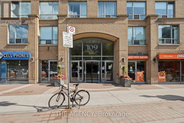 Close-up of the arched entrance to 109 Front Street East apartment building with retail storefronts. - 643 - 109 Front Street E, Toronto