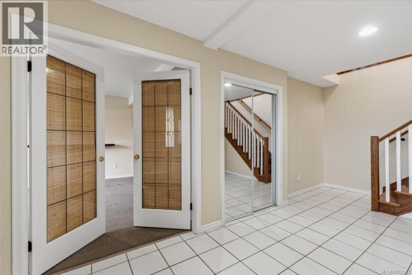 Private backyard with stone patio, mature trees, and fenced perimeter - 6439 Nidri Pl, Nanaimo