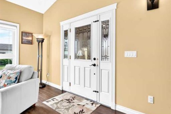 Interior view of a white double door with stained-glass panels and sidelights, leading into a beige room. - 6444 Cedar Way, Innisfail