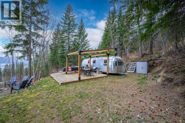 Outdoor seating area with Adirondack chairs around a stone fire pit, overlooking a wide lake and mountains. - 6474 Deer Run Road Lot# 11, Magna Bay