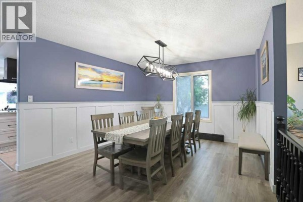 Dining room with a large table set for eight, blue walls, and white wainscoting. - 648 2nd Street E, Brooks