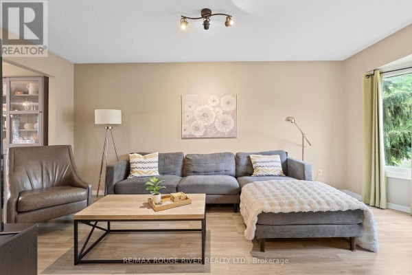 Living room with a grey sectional sofa, leather armchair, and coffee table. - 648 Cognac Crescent, Pickering