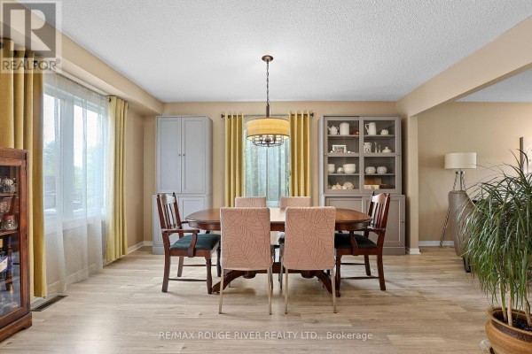 Dining room with a wooden table, upholstered chairs, and display cabinets. - 648 Cognac Crescent, Pickering