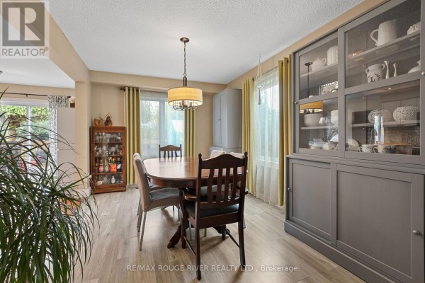 Dining room view with a wooden table, chairs, and a large grey cabinet. - 648 Cognac Crescent, Pickering