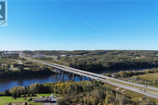 View of a large bridge crossing a river with highway exits and surrounding trees. - 649 Madawaska Road, Grand Sault/grand Falls