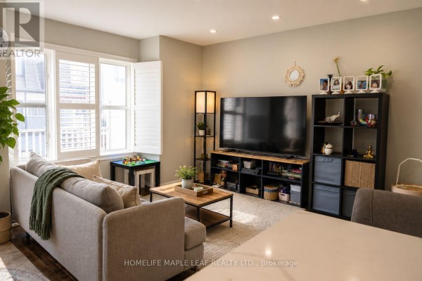 Living room with a grey sofa, large television, entertainment unit, and plantation shutters on the window. - 649 Scott Boulevard, Milton