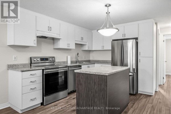 Modern kitchen with white cabinets, stainless steel appliances, and a granite island. - 64a - 1989 Ottawa Street S, Kitchener