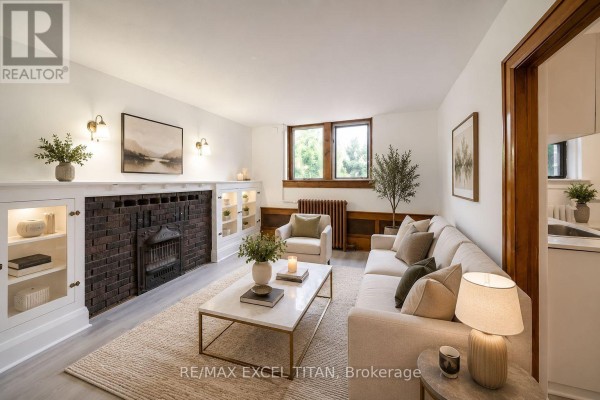 Living room with hardwood floors, brick fireplace, and built-in wooden cabinets. - 65 - 12 Kingston Road, Toronto