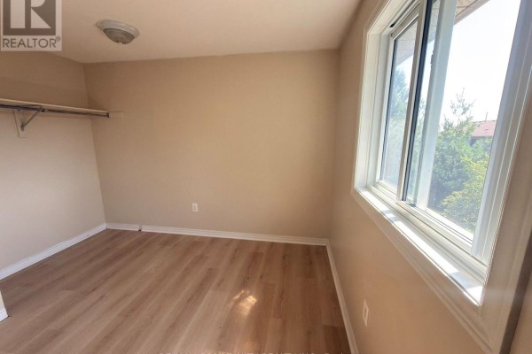 Hallway with light wood laminate flooring, leading to two doorways. - 65 - 511 Admiral Drive W, London East