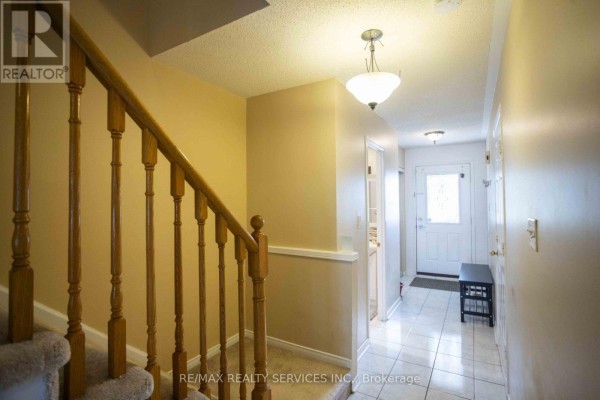 Interior hallway with carpeted stairs, white door, and tiled floor. - 65 - 6830 Meadowvale Town Centre Circle, Mississauga