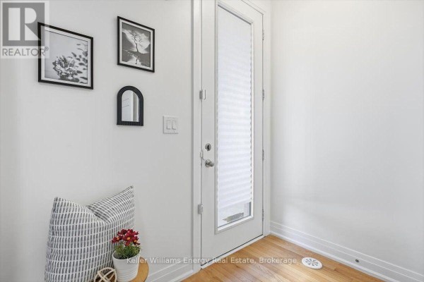 Interior entryway with a white door, wood floor, and wall decor including framed art. - 65 - 721 Lawrence Avenue W, Toronto