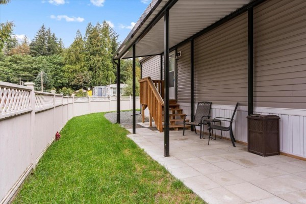 Close-up exterior view of the grey mobile home with a covered porch and white fence. - 65 3942 Columbia Valley Road, Cultus Lake East, Cultus Lake