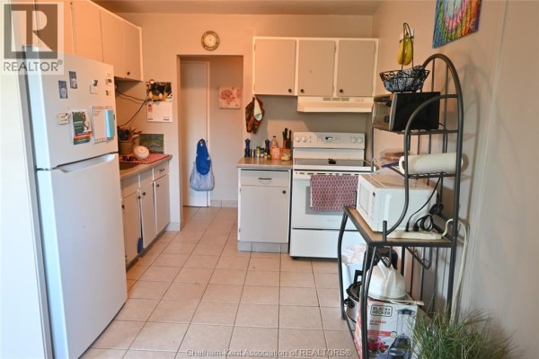 Kitchen with white cabinets, refrigerator, stove, dishwasher, and tiled floor. - 65 Baldoon Road Unit# 11, Chatham