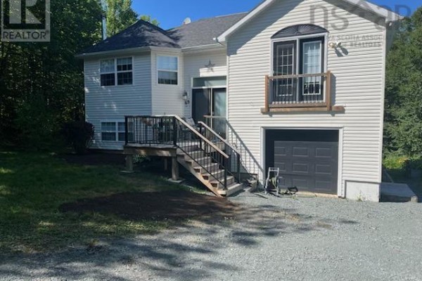 A bright living room with a bay window, fireplace, multiple seating areas, and hardwood floors. - 65 Beamish Road, East Uniacke