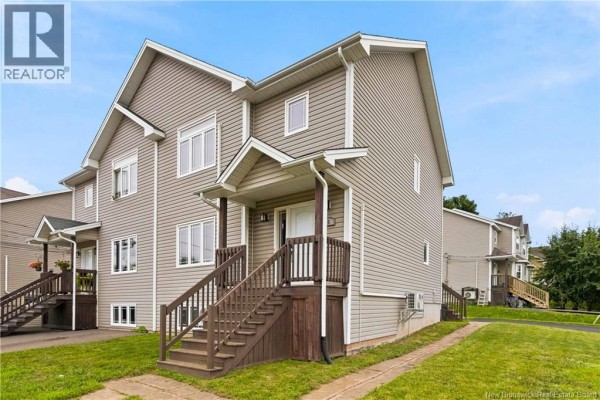 Front exterior of a beige townhouse with white trim and dark wood steps. - 65 Belle-foret, Dieppe