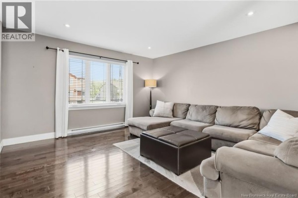 Interior entryway with beige tiled floor, white door, and dark wood staircase. - 65 Belle-foret, Dieppe