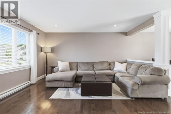 Living room with dark hardwood floors, grey sectional sofa, and large window. - 65 Belle-foret, Dieppe