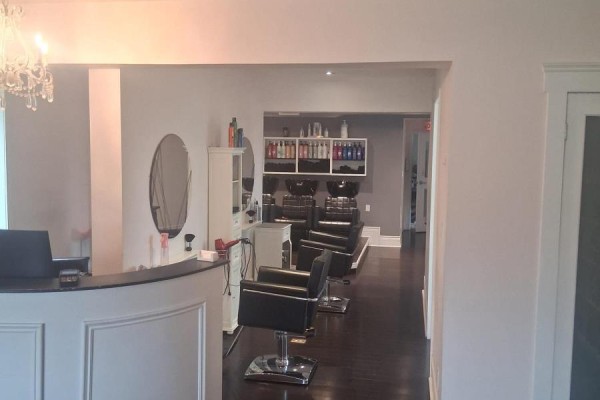 Reception desk area of a salon with black chairs and hair washing stations in background. - 65 Broadway, Orangeville