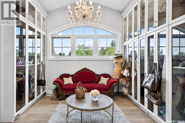 Walk-in closet with red velvet sofa, arched window, and floor-to-ceiling glass cabinetry. - 65 Calypso Drive, Moose Jaw