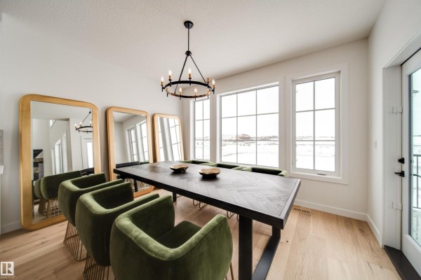 Dining table with herringbone pattern, green velvet chairs, and large windows with a winter view. - 65 Chartres Cl, St  Albert