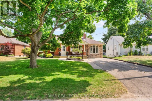 Exterior view of a residential house with a green lawn and mature trees. - 65 David Street, London South