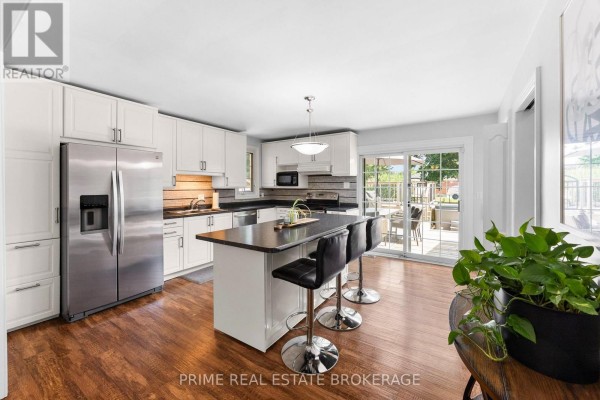 Modern kitchen with white cabinets, stainless steel appliances, and a black island. - 65 David Street, London South