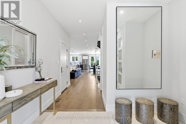 Hallway looking into an open-concept living area with hardwood floors and a large mirror. - 65 Forest Avenue, Mississauga