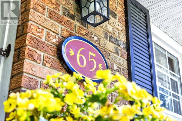 Close-up of a maroon and gold house number '65' on a brick wall. - 65 Maplewood Drive, Amaranth