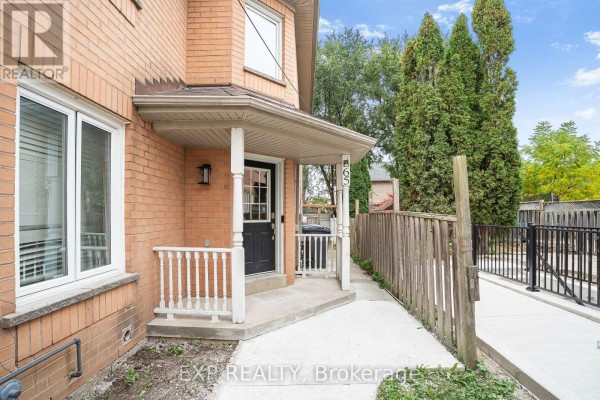 Front entrance porch of townhouse with white railings and black door. - 65 Pressed Brick Drive, Brampton