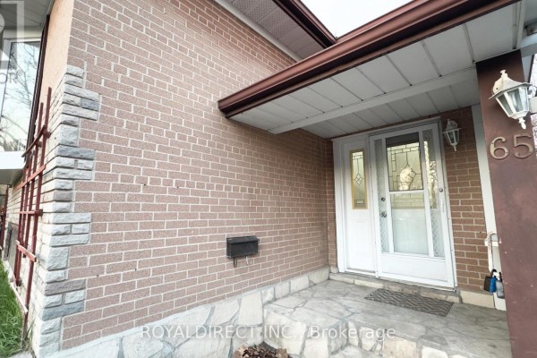 View of the driveway and front yard with a residential street in the background. - 65 Sharbot Avenue, Toronto