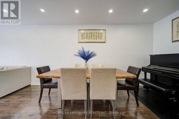 View of a dining table with chairs, dark hardwood floors, and a piano in the room. - 65 Shepton Way, Toronto