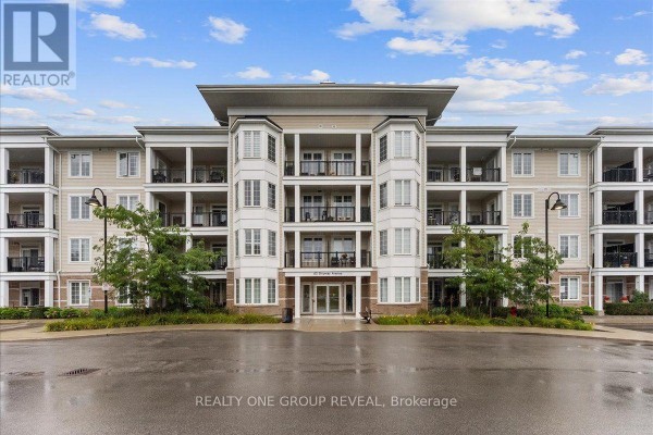 Front view of a beige apartment building with a central entrance and balconies. - 111 - 65 Shipway Avenue, Clarington