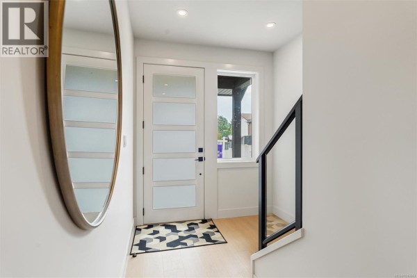 Entranceway with a white front door featuring frosted glass panels and a large oval mirror. - 650 Wisteria Ridge, Langford