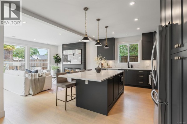 Open concept living and kitchen area with a large island, fireplace, and view of the backyard. - 650 Wisteria Ridge, Langford