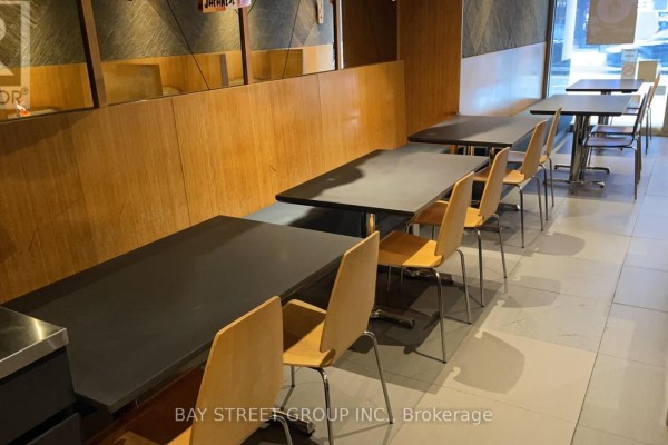 Dining area featuring multiple black tables and wooden chairs - 650 Yonge Street, Toronto