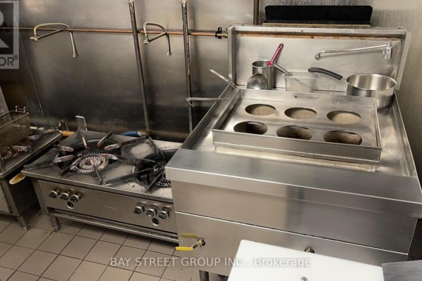 Close-up of stovetop with pots and frying equipment in commercial kitchen - 650 Yonge Street, Toronto