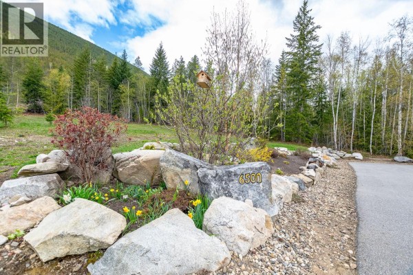 Entrance landscaping with large rocks, daffodils, and a birdhouse on a tree. - 6500, 6450, 6425 1 Avenue Nw Lot# 1,2,3, Salmon Arm