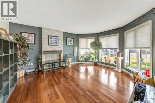 Spacious living room featuring hardwood floors, a bay window with multiple panes, and wall decor. - 6501 39 Street, Lloydminster